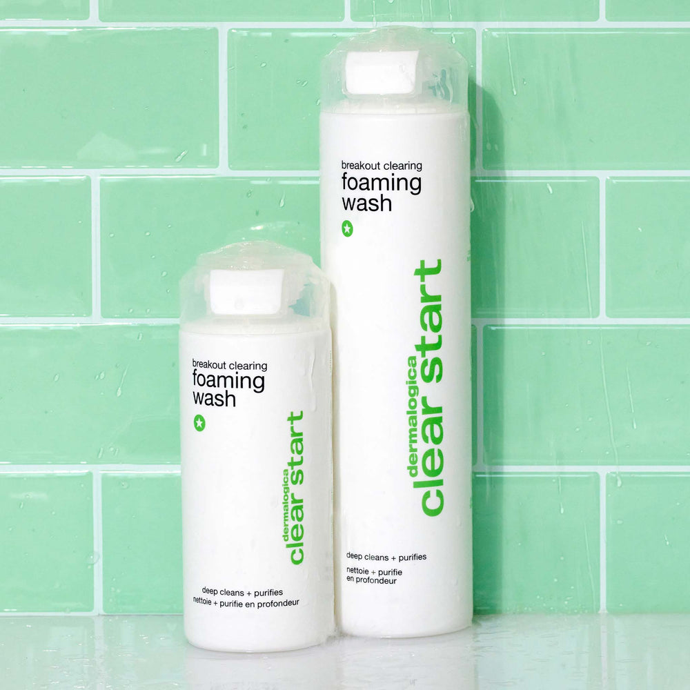 Two bottles of Dermalogica foaming wash against a green tiled wall.