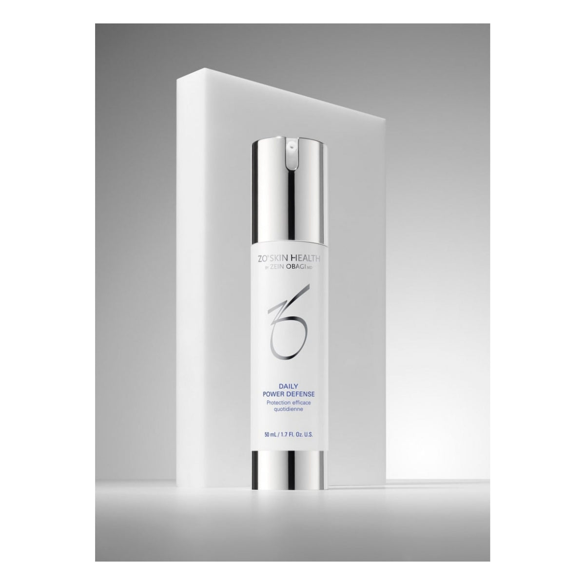 A bottle of ZO Skin Health Daily Power Defense 50mL displayed in front of its white rectangular packaging box on a gray gradient background.