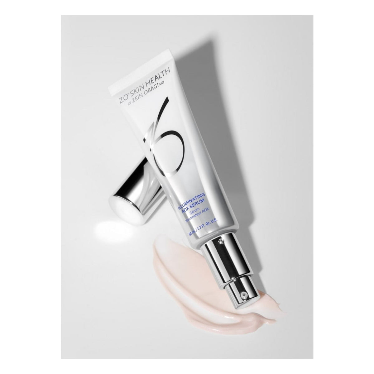 ZO Skin Health Illuminating AOX Serum 50mL in a white squeeze tube with a silver cap, shown with a smear of pale pink cream on a light gray background.