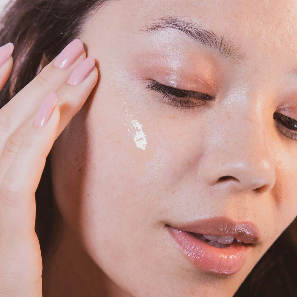 Close-up of a woman's face with biolumin-c serum on her cheek
