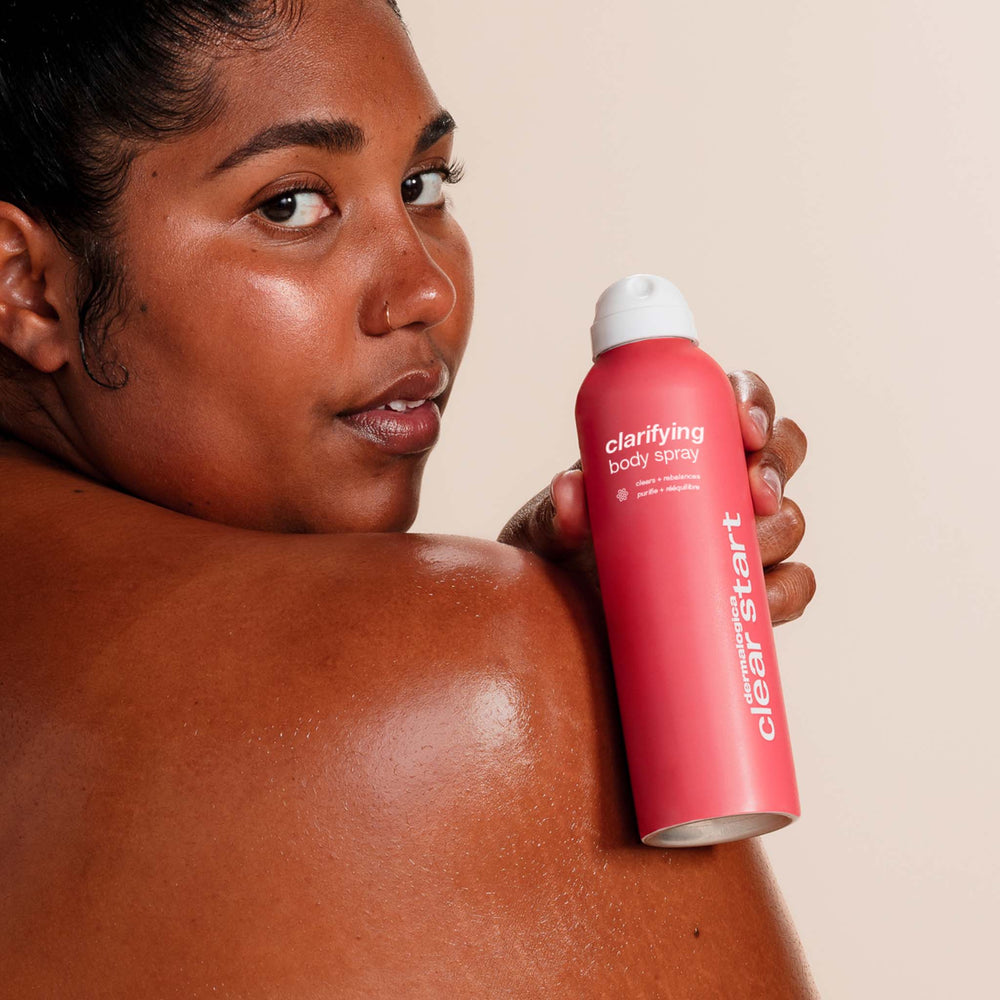 Person holding a red 'clearstart' clarifying body spray can on a beige background